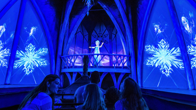 Guests on a boat looking towards an animatronic of Elsa surrounded by snowflake projections.