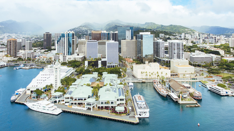 Aerial view of boats docked at Honolulu harbor with tall buildings and mountains in background