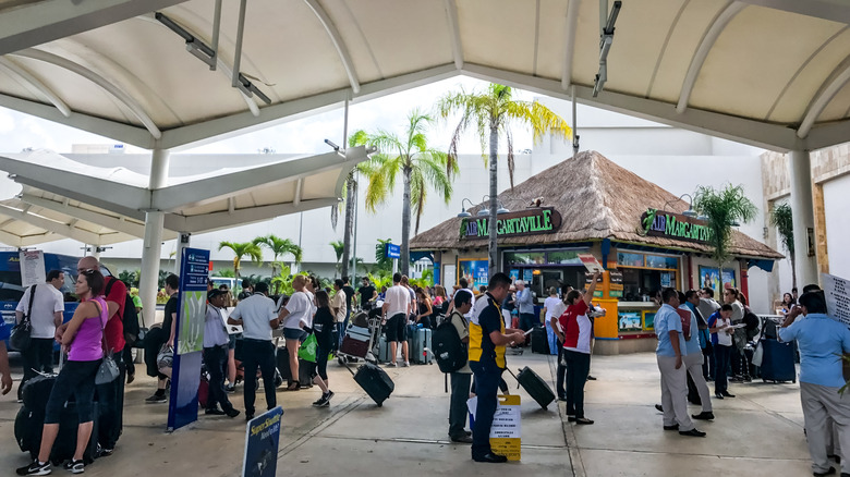 Passengers arriving at the Cancun Airport are surrounded by locals offering them transportation