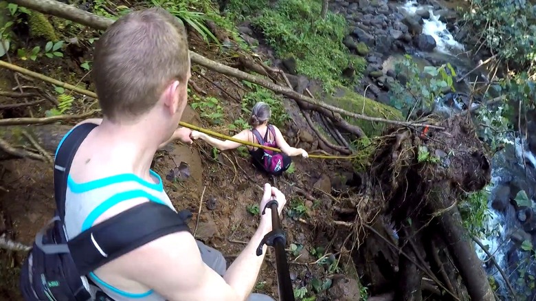 Two hikers clamber down steep slope on The Makaleha Trail