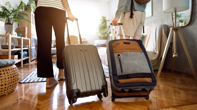 people dragging luggage into home