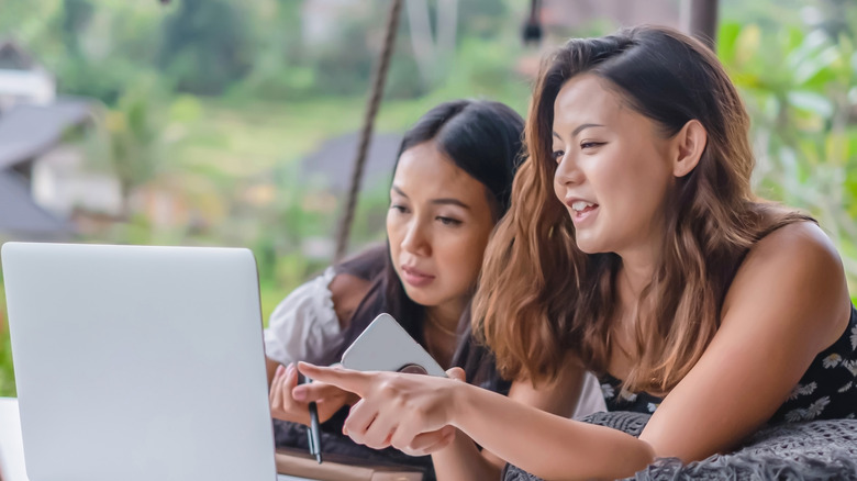two women look at laptop together