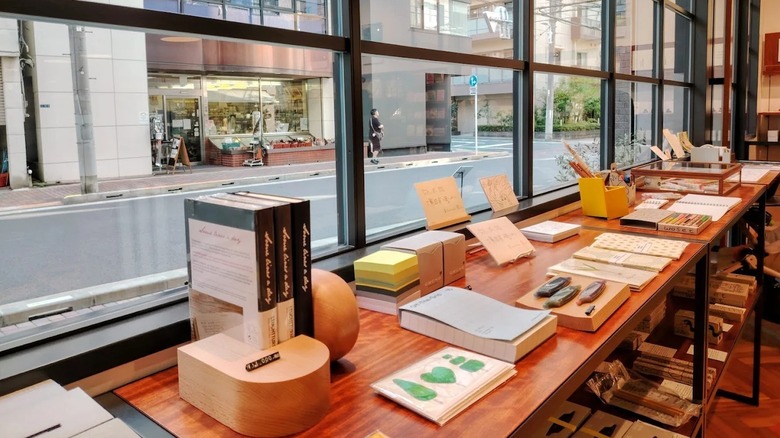 Stationery and books lined on a wooden table against a glass window overlooking street