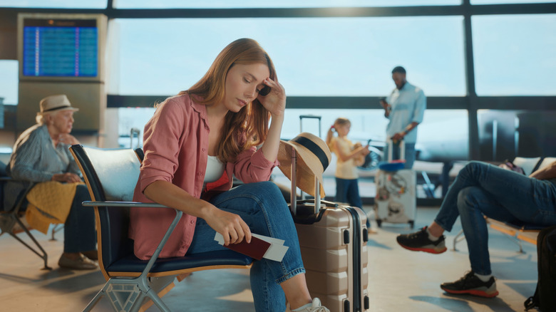 woman sitting at the gate and looking stressed in an airport