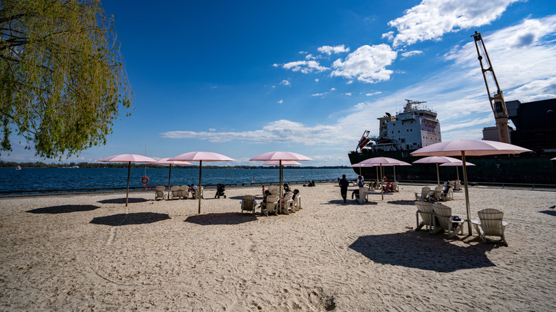 People relaxing under the signature pink umbrellas of Sugar Beach in Toronto
