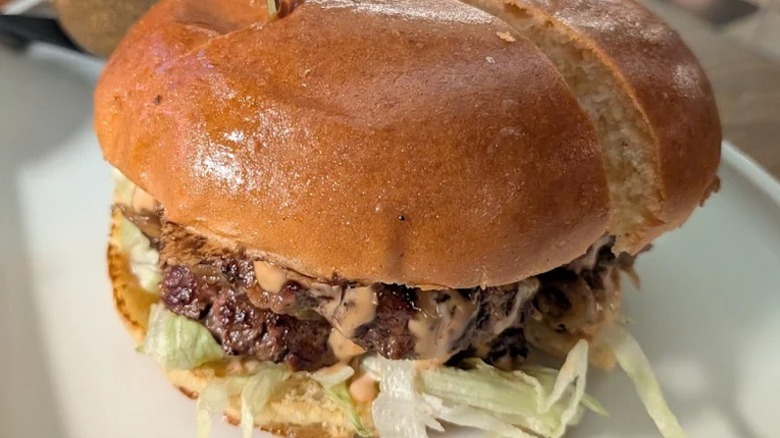 A juicy Gladstone Burger served at the hotel's Cassette restaurant on a white plate.