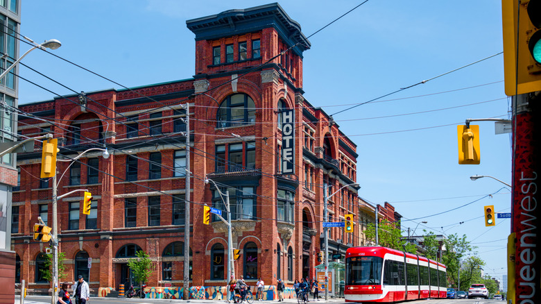 The historic red-brick facade of Gladstone House with the Toronto light rail and pedestrians outside.