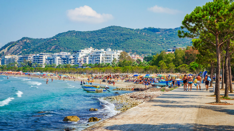 The coastal city of Vlora, Albania, with a crowded beach and buildings in the background, pictured on a sunny day