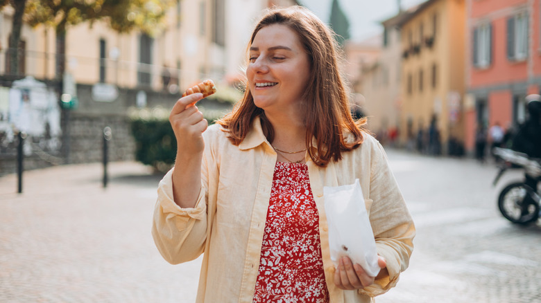 Traveler eating a snack while walking in Italy