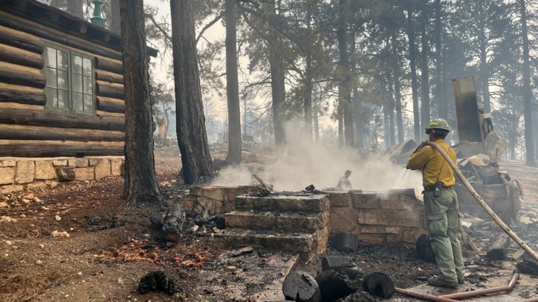 Firefighters stand near the smoldering remains of the Grand Canyon Lodge