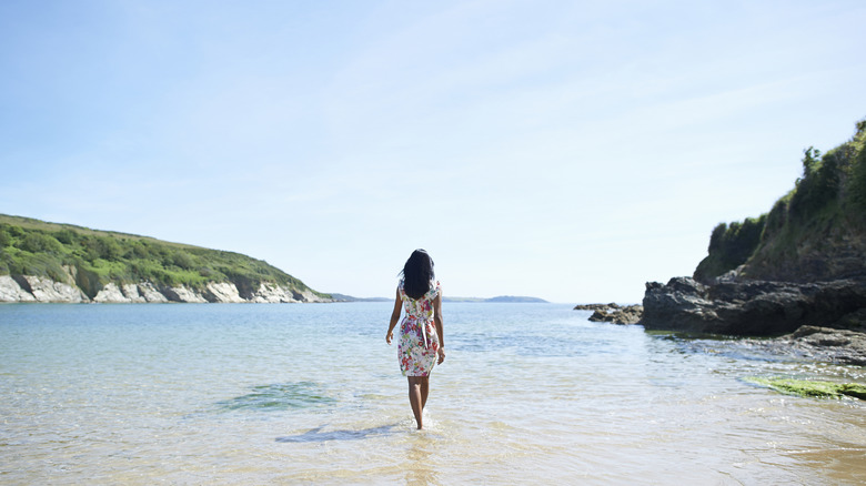Woman wearing a flower-print dress strolling solo on a beach