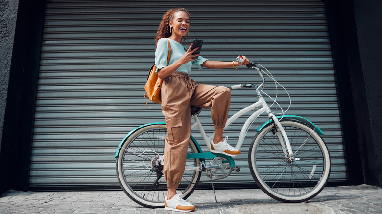 Woman pausing in her bike ride to look at messages on her phone
