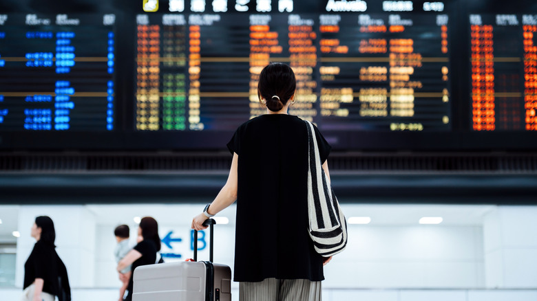 A woman looks up to the flight list at the airport