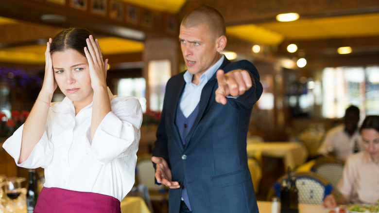 Angry man in a restaurant yelling at young waitress