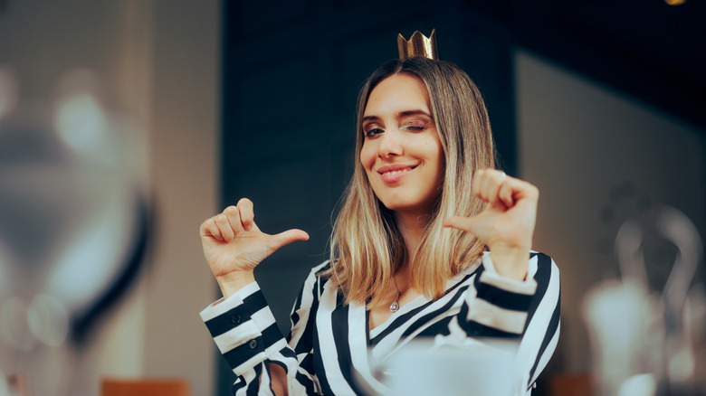 Cheerful woman wearing a crown and looking overly pleased with herself.