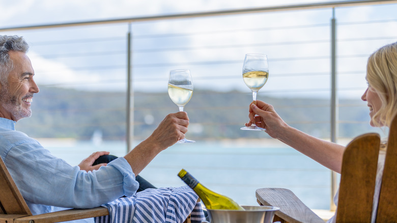 Two adults drinking wine on their balcony on a cruise ship