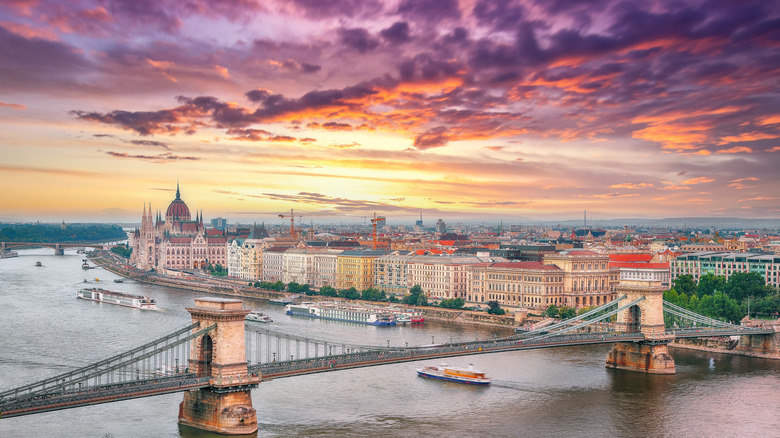 View of bridge over Danube river, sunset skies, parliament building in the backdrop