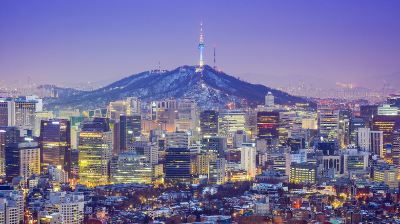 Glimmering city skyline in purple twilight with mountain in the backdrop
