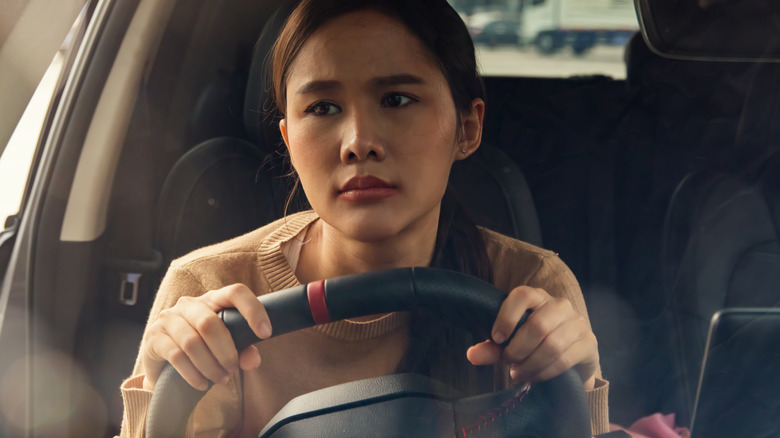 A woman looks displeased while driving a car in traffic