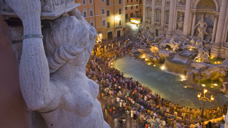 Large stone statue overlooking crowded historic fountain