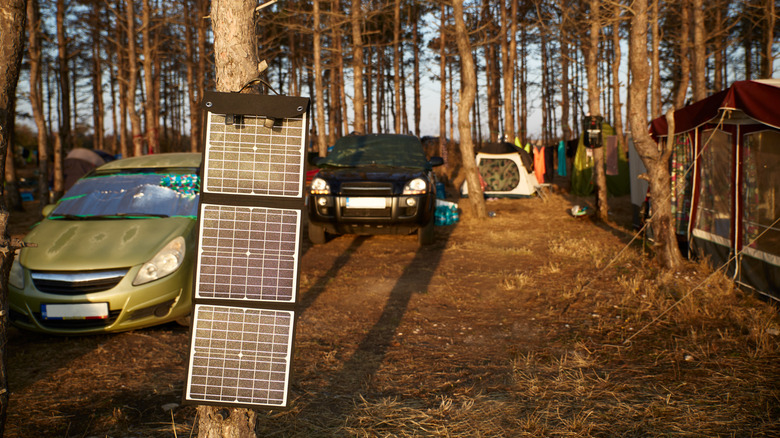 cars and tents at campsite with solar panels in foreground