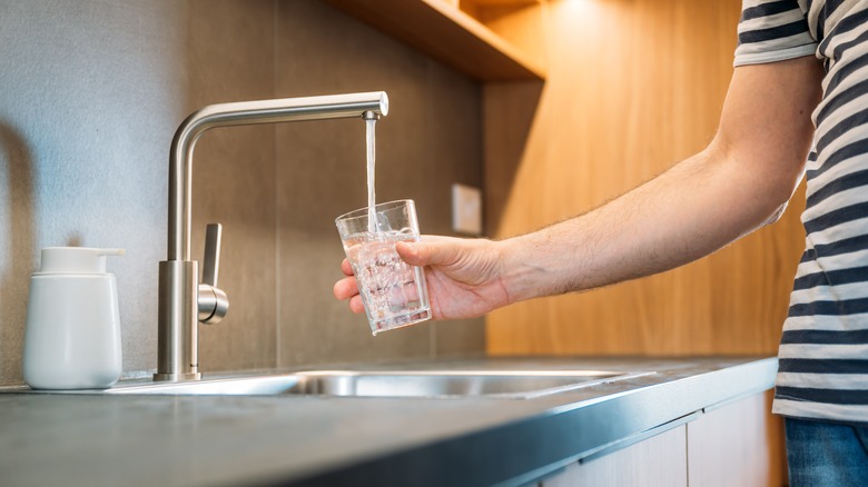 Someone pouring water from a tap into a glass