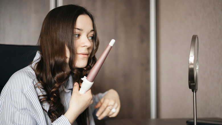 Person using a cordless curling iron at a hotel