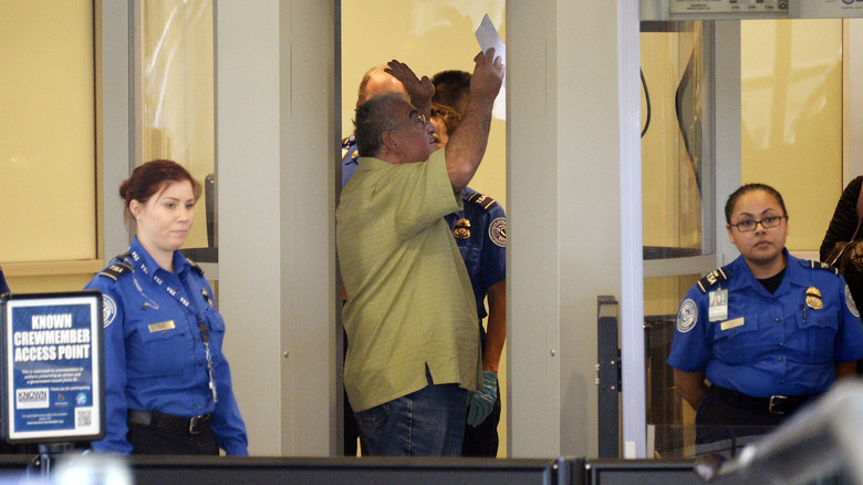 A traveler steps into the security screening as Transportation Security Administration agents look on after Terminal 3 was re-opened a day after a shooting at Los Angeles International Airport November 2, 2013 in Los Angeles, California.