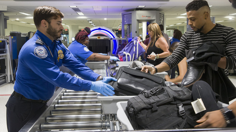 TSA agent and passenger scanning luggage with CT scanner