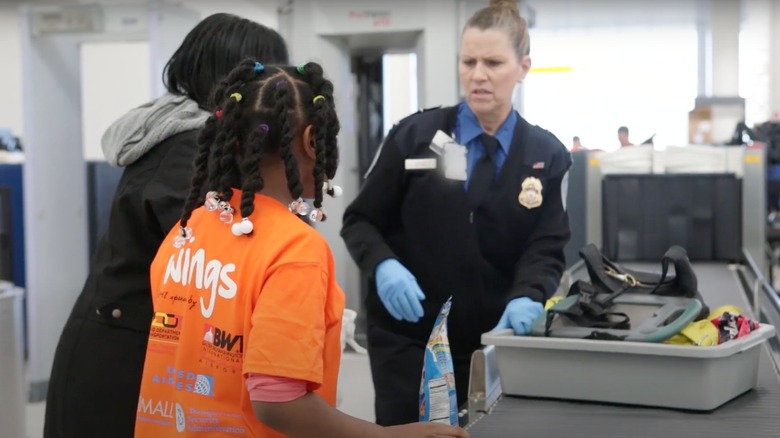 Child and woman going through an airport security checkpoint