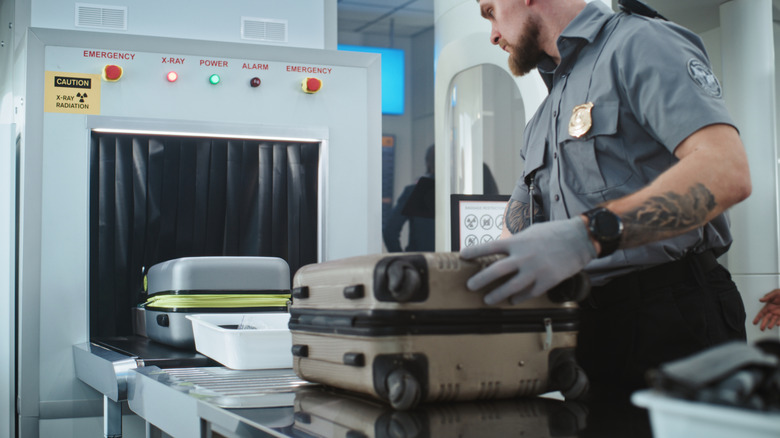 a security screener places luggage on the X-ray machine for airport security checks