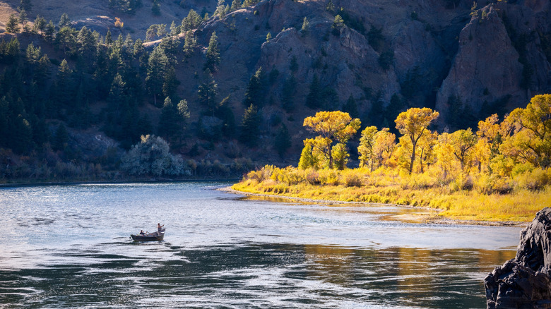 Boat on Missouri river surrounded by trees and rocky bluffs