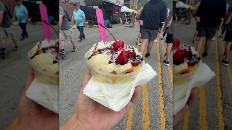 Hand holding banana treat with cherry and coconut