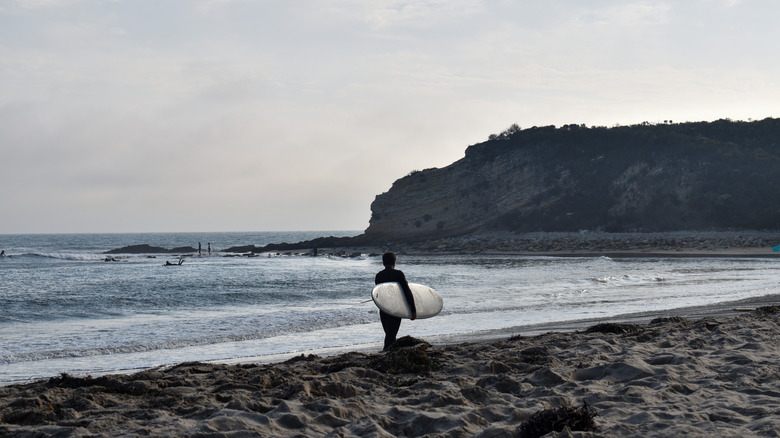 A surfer walks to the waves on Refugio State Beach