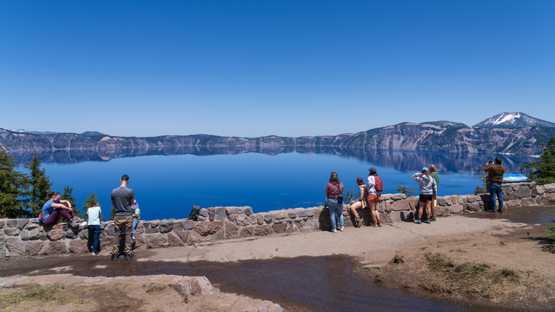 People stand at a viewpoint near Rim Village overlooking a large lake in Crater Lake National Park