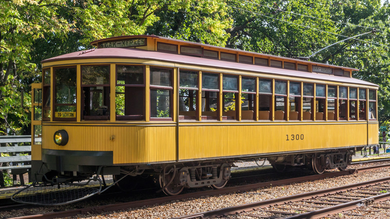 Historic yellow streetcar on tracks in front of trees