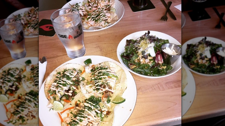 Tacos, cup of water, and salad on a wooden table from Side A Brewing