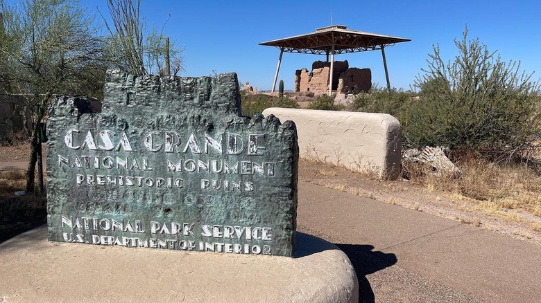 Stone sign reading "Casa Grande National Monument" with monument in background