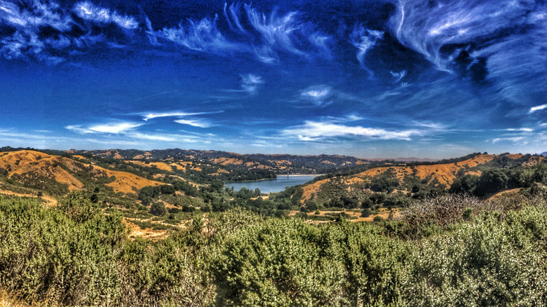 Scrub hills lead to Lafayette Reservoir under swirling clouds