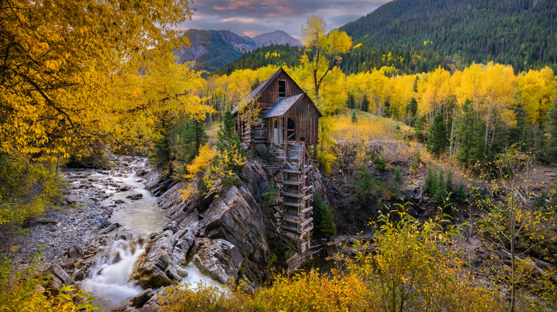 Crystal Mill in Marble, Colorado with a small waterfall, an old abandoned building, and fall colors on trees
