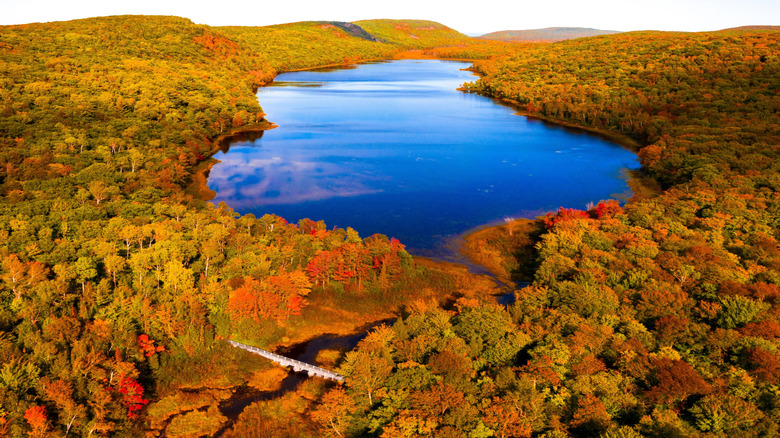 Overhead drone shot of Lake of the Clouds in Michigan, surrounded by vibrant autumn foliage.