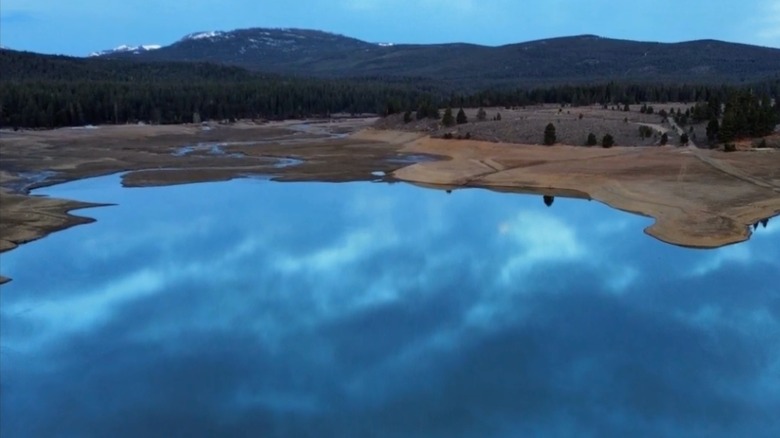 Drone footage of Prosser Creek Reservoir in northern California's Sierra Nevada mountains with reflection of clouds in calm lake