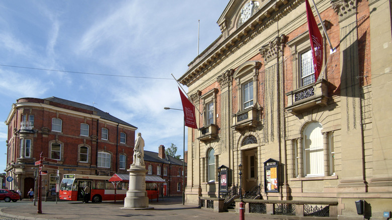 The Victorian Town Hall in Kidderminster, England with a statue in front and a bus and brick building in the distance