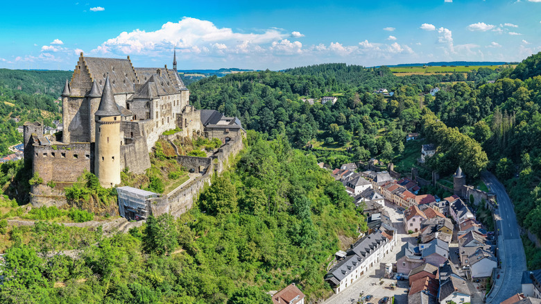 Vianden Castle atop a hill overlooking modern houses in Luxembourg.