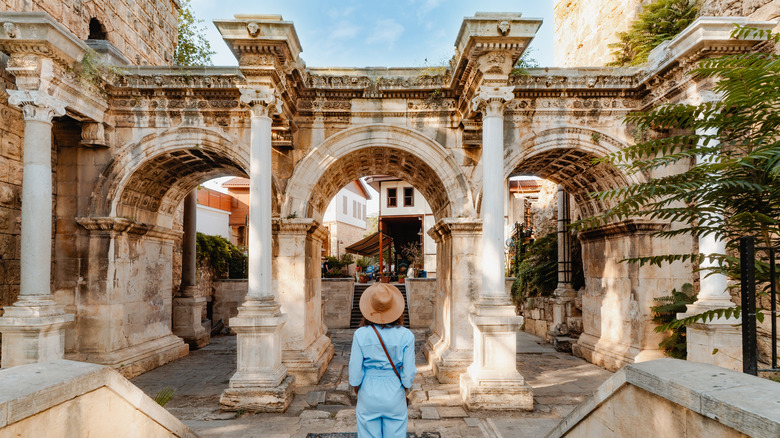 A woman stands in front of an ancient Roman gate