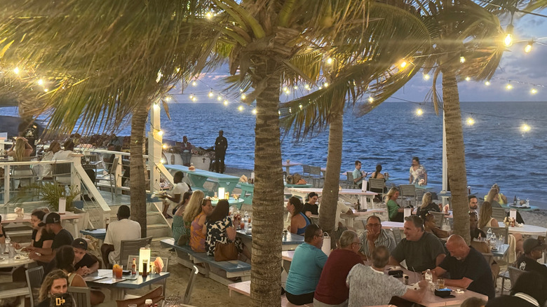 Da Conch Shack Restaurant and Rum Bar with its ocean-front tables on the sand and palm trees strung with lights
