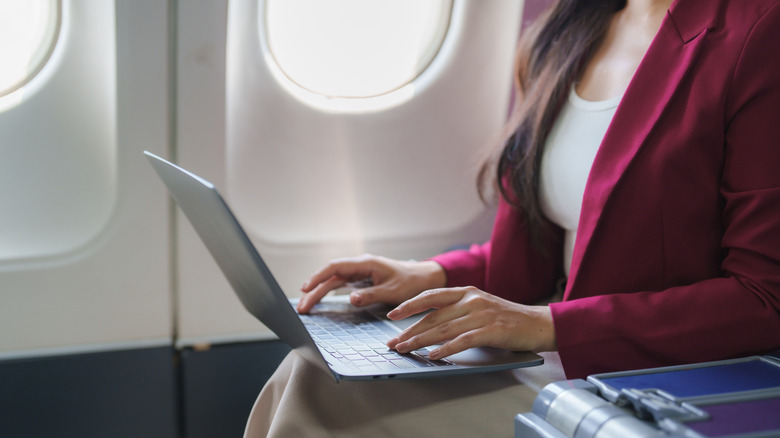 A woman uses in-flight Wi-Fi on her laptop