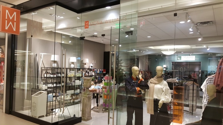 The shopfront at Mona Williams filled with laundry soaps and two mannequins showcasing women's clothing.