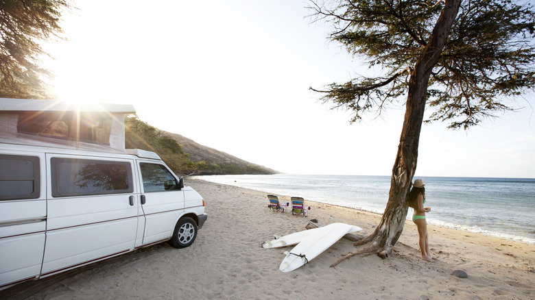 Hawaii RV parked on beach with a woman leaning on a tree