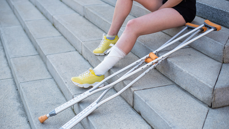 Women with two crutches, sitting on stairs